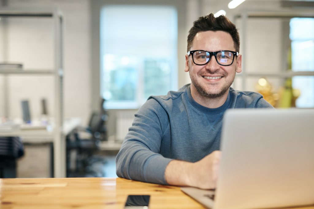 Stock image of a man smiling at his laptop